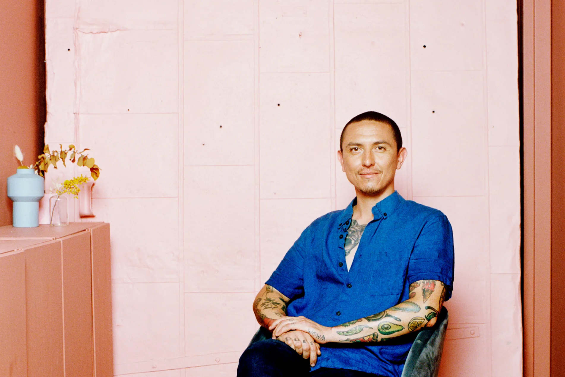 Chef Alan Delgado seated against a pink wall